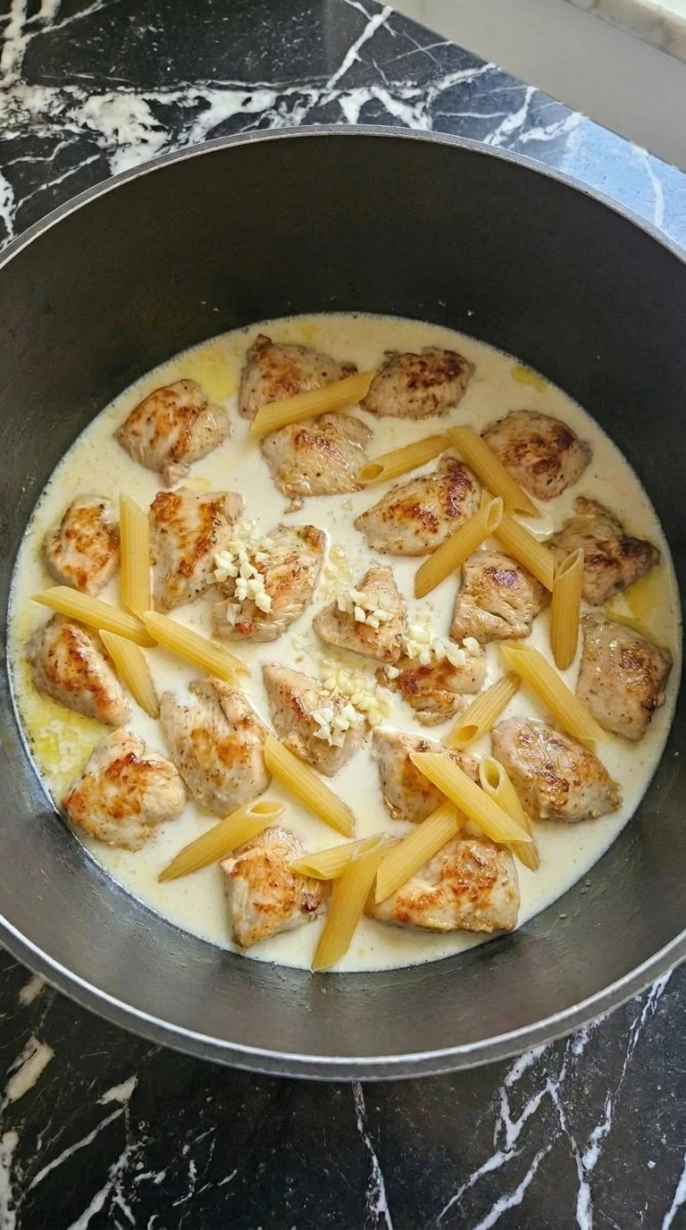 Penne and creamy cooking liquid added with chicken for One Pot Chicken Alfredo Pasta