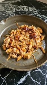 Shredded barbecue chicken mixed with softened onion for BBQ Chicken Sliders.