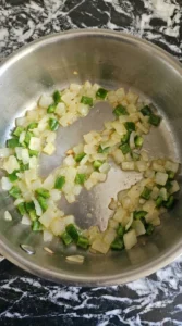 Yellow onion and jalapeno pepper softening in butter for Cheesy Queso Dip.