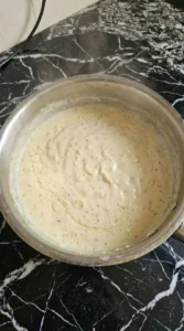 Cream and parmesan thickening into alfredo sauce in a saucepan.