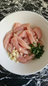 Raw chicken strips and measured ingredients prepared for Alfredo pasta