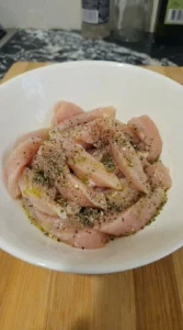 Seasoned chicken resting in bowl before Alfredo assembly