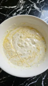 Alfredo sauce thickened with parmesan and milk in white bowl