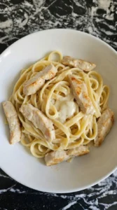 Cooked fettuccine and chicken coated in creamy Alfredo sauce