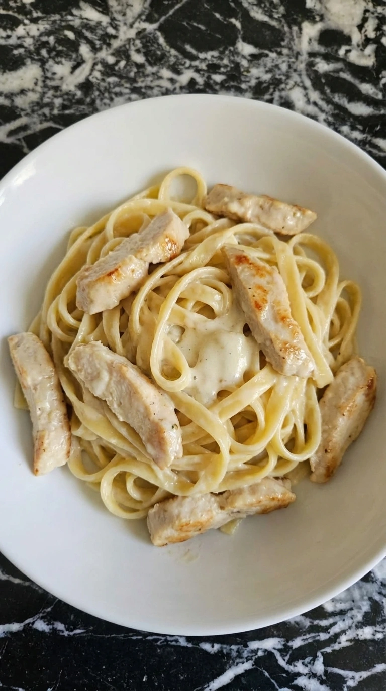 Cooked fettuccine and chicken coated in creamy Alfredo sauce