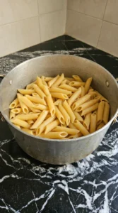 Cooked penne in a large pot after boiling until tender.