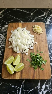 Diced onion chopped garlic chopped cilantro and lime wedges for Easy Ground Beef Tacos.