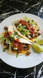 Served Easy Ground Beef Tacos with salsa cilantro and lime on a white plate.