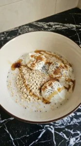 Rolled oats mixed with milk yogurt chia and cinnamon in a bowl.