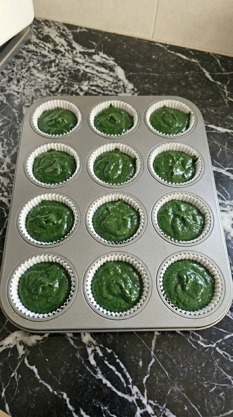 Twelve cupcake liners filled with green velvet batter