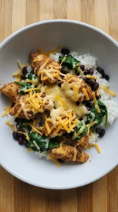 Cheese softened unevenly over chicken and rice bowl