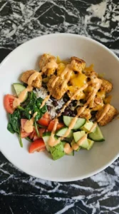 Fresh toppings and creamy sauce added to a chicken protein bowl