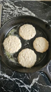 Four rounds of High Protein Pancake batter cooking in a skillet.
