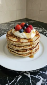Plated High Protein Pancakes with yogurt berries and maple syrup.