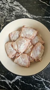 Chicken thighs coated with cornstarch and seasoning for Honey Garlic Chicken.