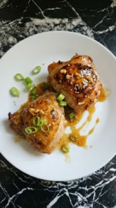 Plated Honey Garlic Chicken with green onions and sesame seeds.