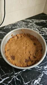 Pressed Biscoff crumb crust in a cake pan.