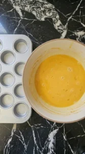 Eggs and milk whisked into a smooth golden mixture for breakfast muffins