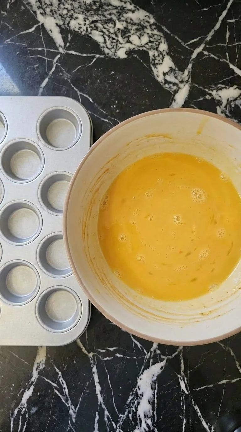 Eggs and milk whisked into a smooth golden mixture for breakfast muffins