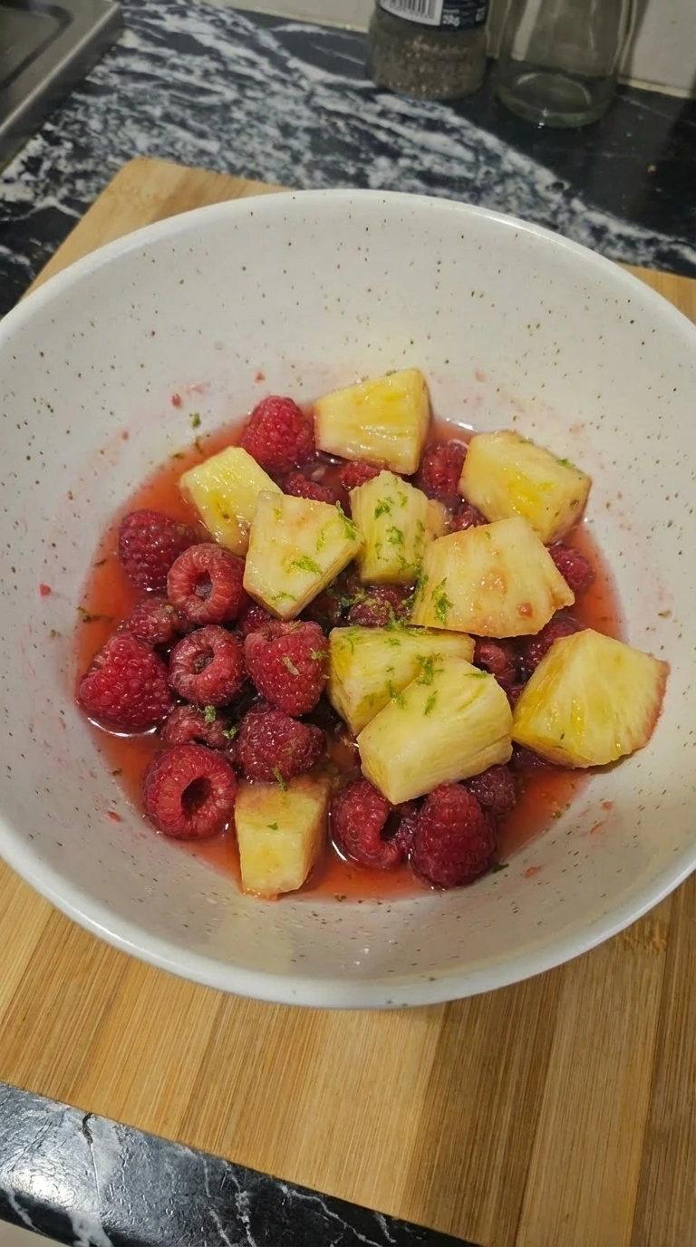 Softened raspberries and pineapple in rosy syrup