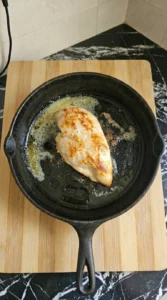 cooked chicken breast resting on plate with natural juices