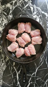 raw chicken thighs seasoned unevenly in skillet