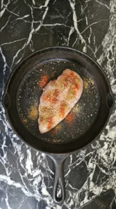 raw chicken breast seasoned with spices unevenly on surface