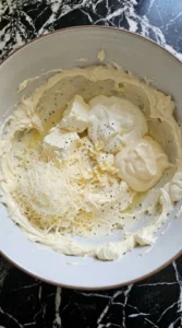Creamy base for Spinach Artichoke Dip mixed with dairy garlic and Parmesan.