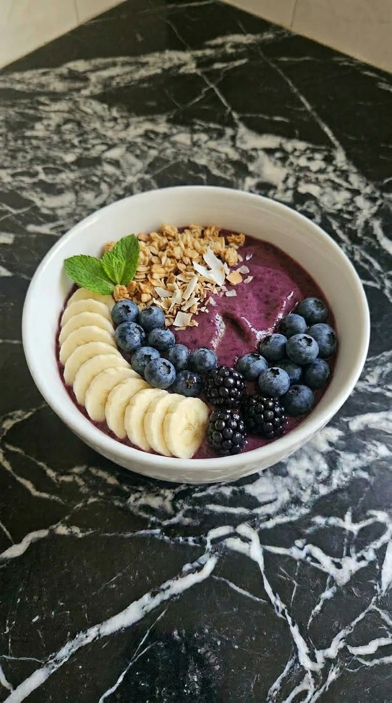 A thick purple berry smoothie bowl topped with banana and blackberries