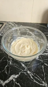 Creamed butter and sugar mixture inside a clear glass bowl
