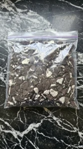 Crushed chocolate cream cookies inside a clear plastic storage bag showing fine and coarse pieces.
