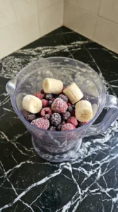 Frozen mixed berries and banana chunks in a blender jar