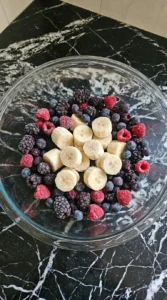 Frozen banana slices and mixed berries in a glass bowl