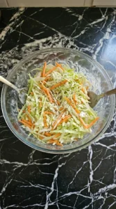 Tossing shredded cabbage and carrots with creamy dressing.
