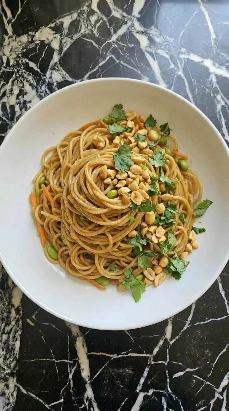 A close-up of a plated cold noodle salad with peanuts and cilantro garnish