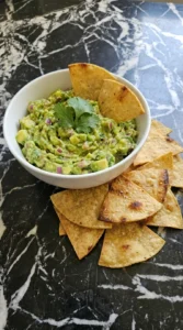 A served portion of guacamole with crispy tortilla chips