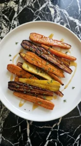 Plated roasted carrots with honey glaze and fresh thyme.