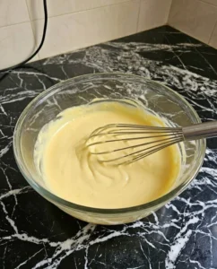 Mixing mayonnaise and mustard in a glass bowl with a whisk