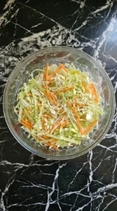 Finished creamy coleslaw seasoned with poppy seeds and pepper.