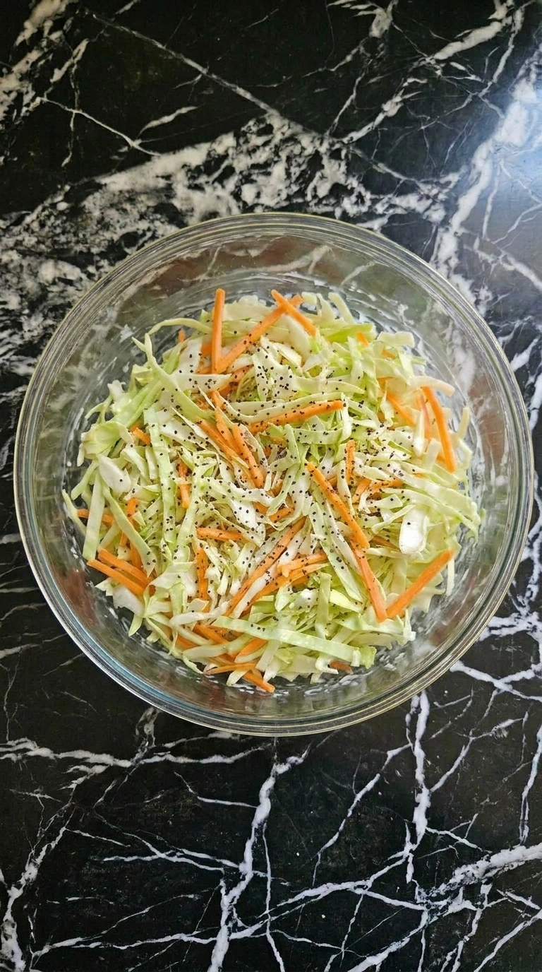 Finished creamy coleslaw seasoned with poppy seeds and pepper.