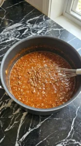 Finely textured ground beef chili simmering in a saucepan