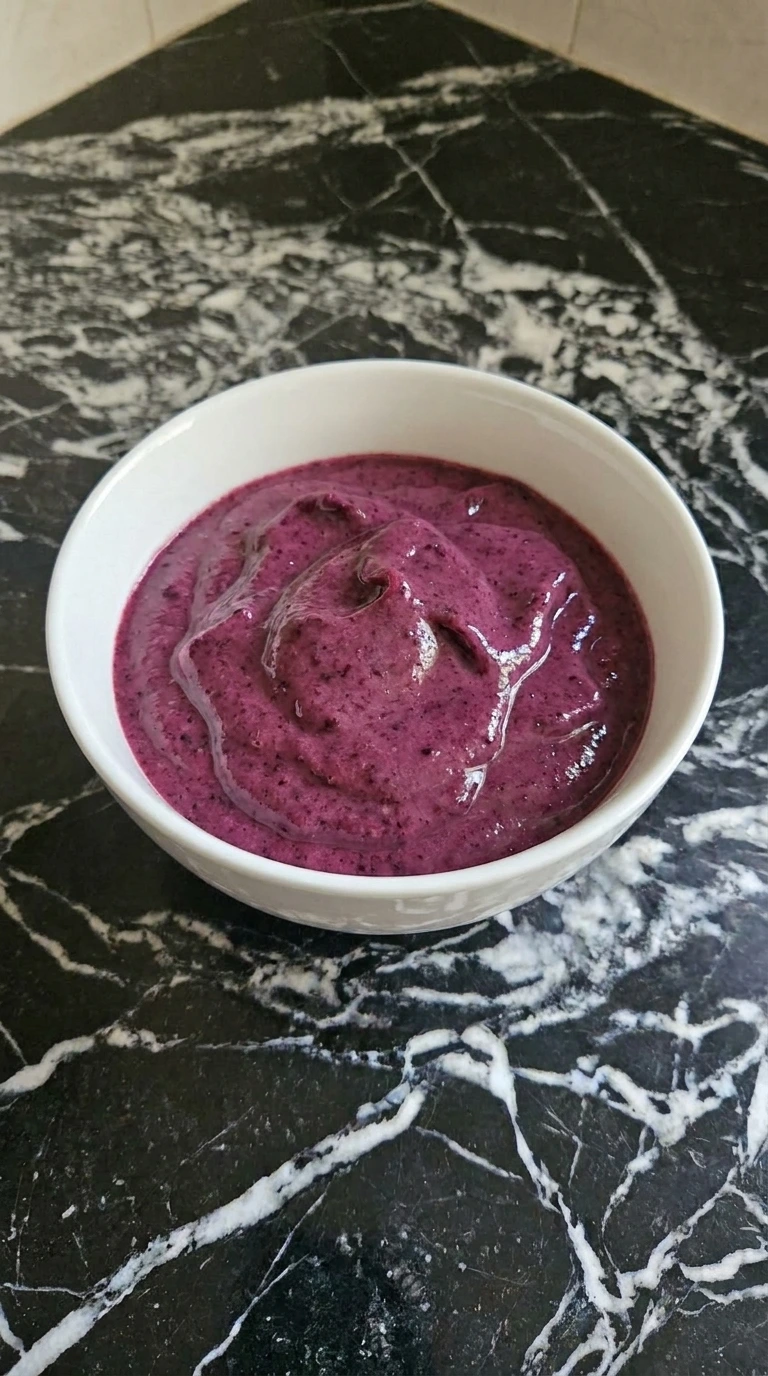 Purple smoothie base poured into a white ceramic bowl