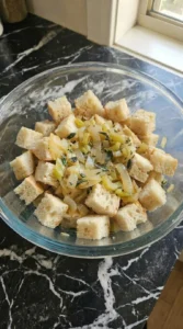 Moist sourdough bread cubes absorbing broth in a glass bowl