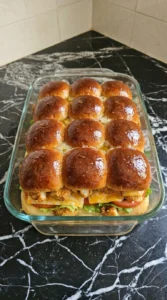 Brushing a glossy hot honey glaze onto the top buns of chicken sliders