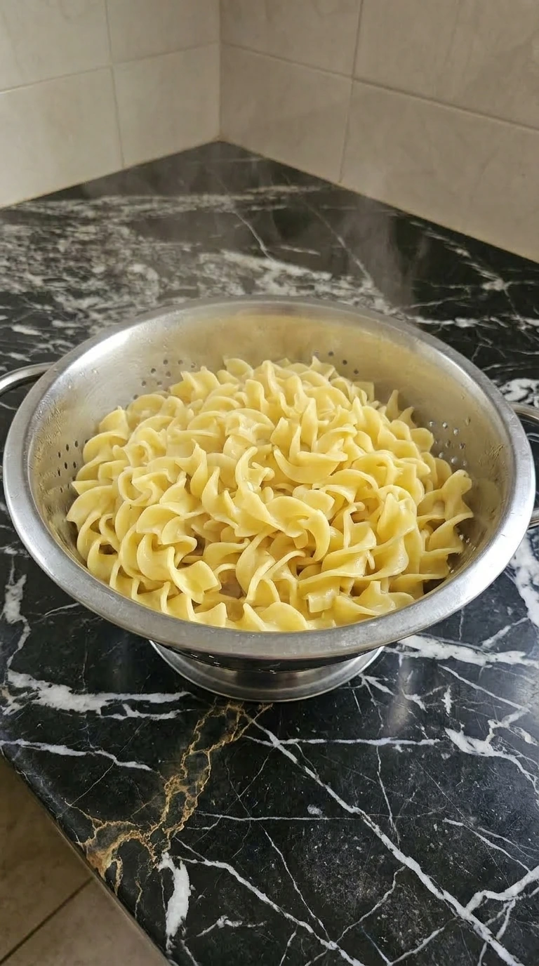 Boiled wavy yellow egg noodles in a colander