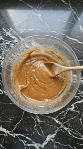 Melted butter and sugars mixed into a thick caramel paste in a glass bowl