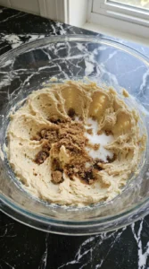 Creamed butter and sugars blended together in a glass mixing bowl.