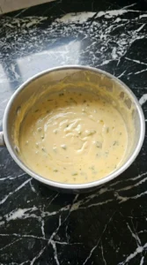 Thick glossy melted cheese dip in a stainless steel saucepan