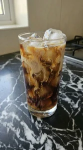 Whole milk blending into dark iced coffee inside a tall glass