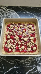 Layered raspberry filling and oat crumble before baking